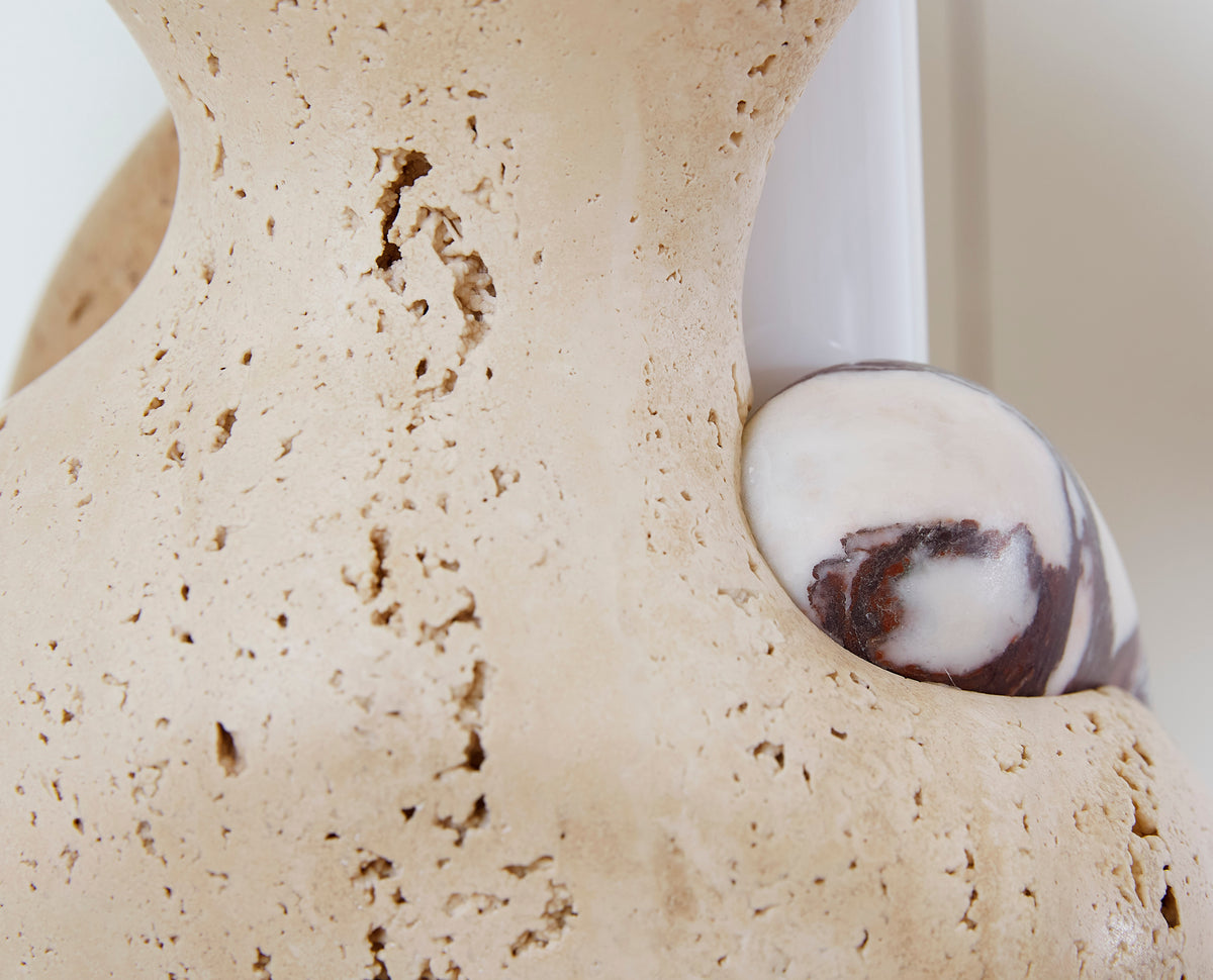 Close-up of a textured marble lamp with a white glass shade. 