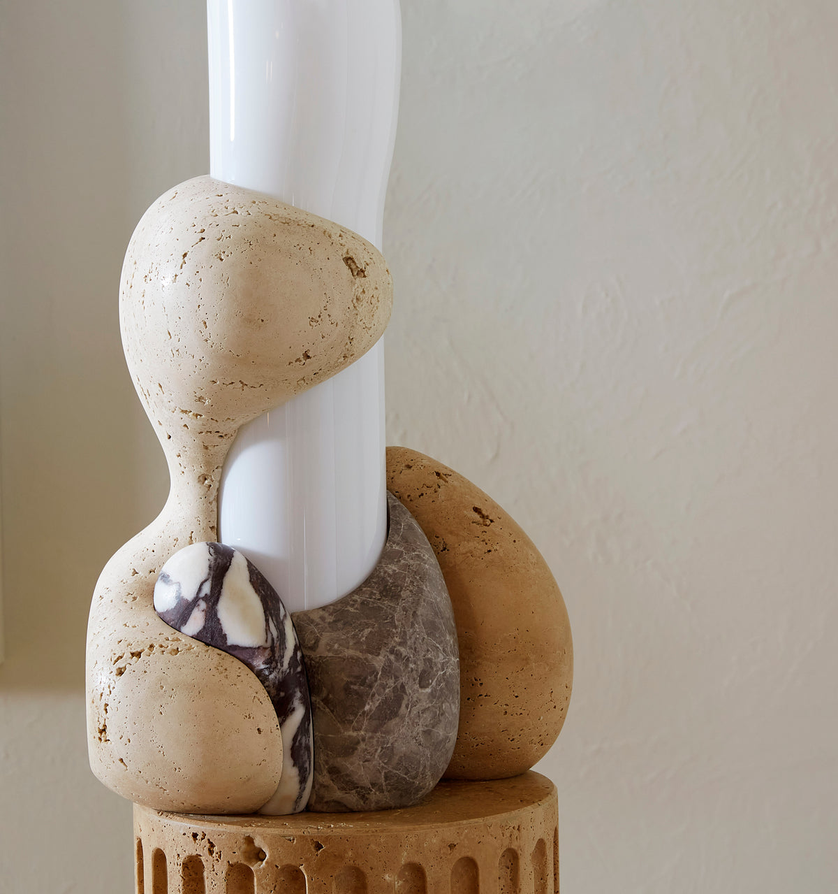 Floor lamp made of marble with a white glass cylinder shade on a neutral background.
