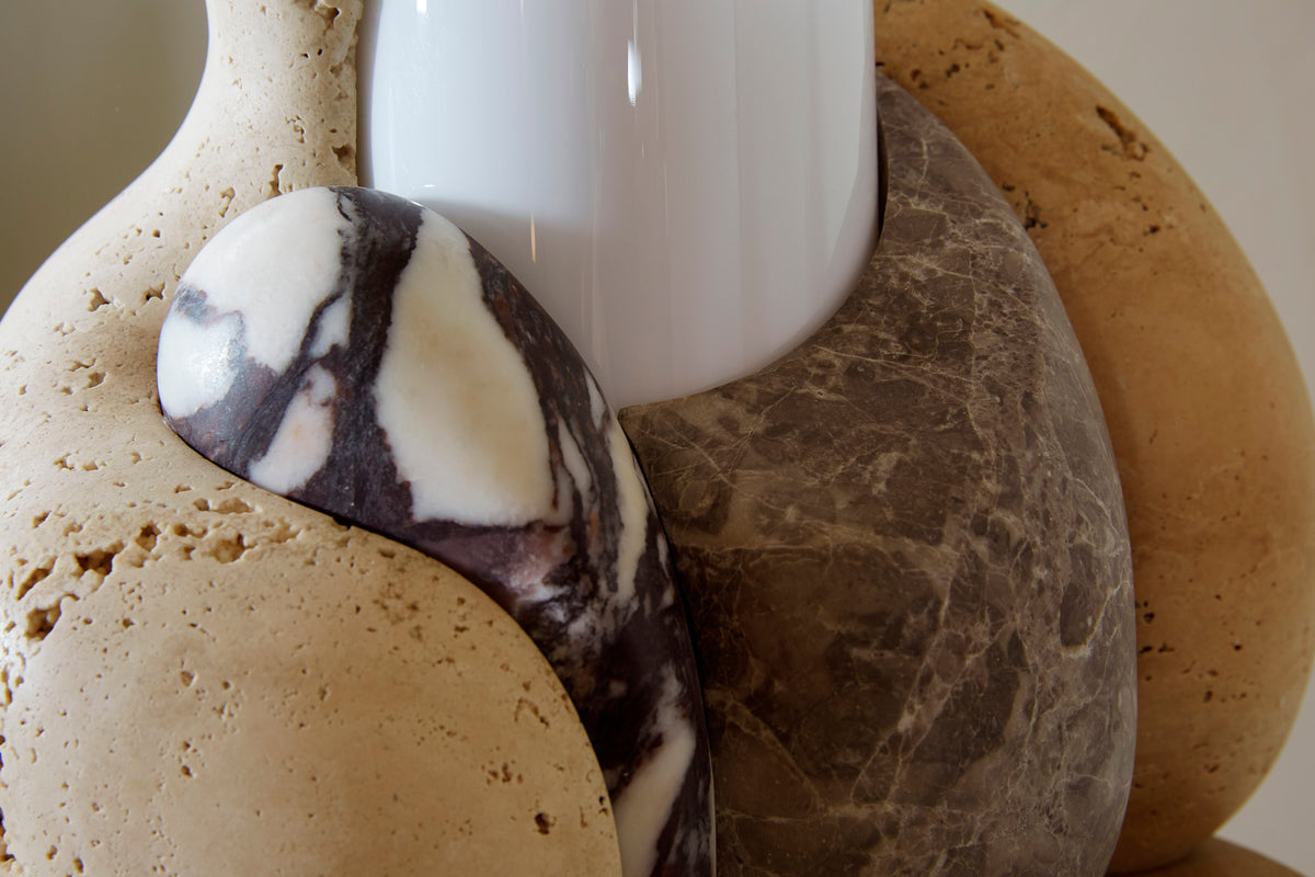 Close-up of marble shapes surrounding a white glass lampshade cyclinder.