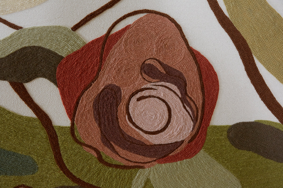 Close-up of a crewel work fabric with a floral pattern in earthy tones.