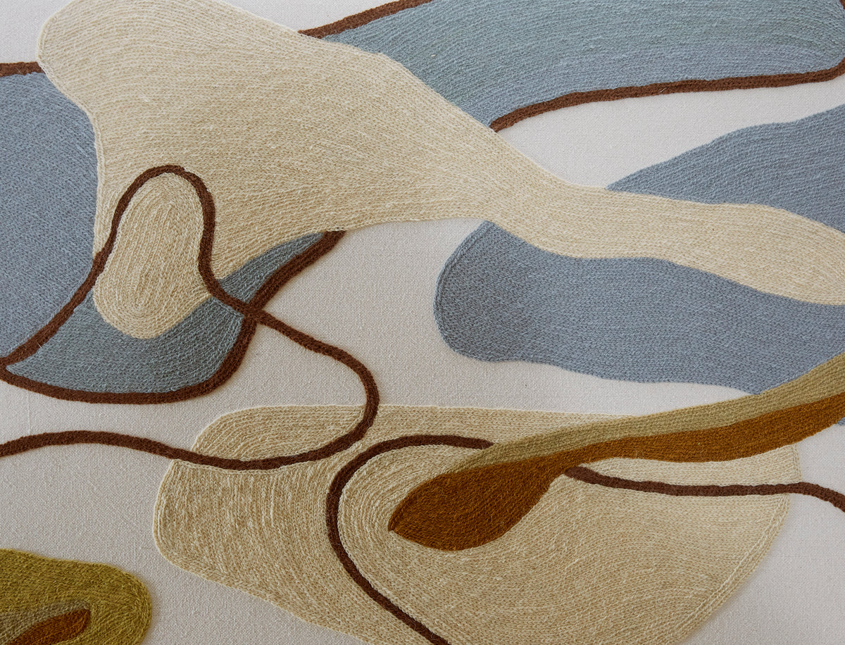 Close-up of a crewel fabric with abstract patterns in beige, brown, and gray.